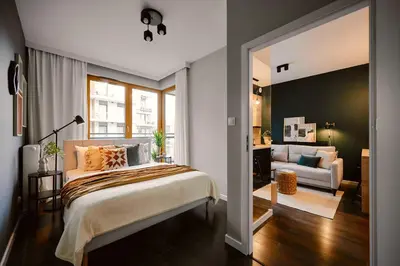 a bedroom with a bed and a living room at Przytulny Apartament Greenwall in Kraków