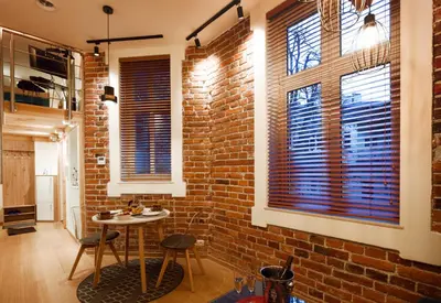 a room with a brick wall and a table and two windows at Wawel Corner Apartment in Kraków
