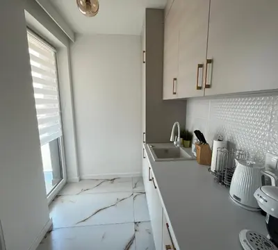 a white kitchen with a sink and a window at Apartament in Bochnia