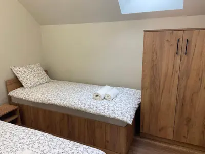 a bedroom with two beds and a wooden cabinet at 3 JASKÓŁKI in Kasina Wielka