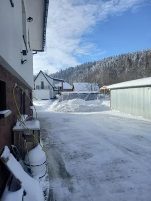 a snow covered street with a house and a building at Agroturystyka Yvonne in Zawoja