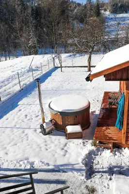 a hot tub in the snow next to a cabin at Agroturystyka Yvonne in Zawoja