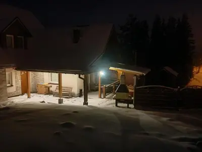 a house in the snow at night with a light at Noclegi Gal in Odrowąż