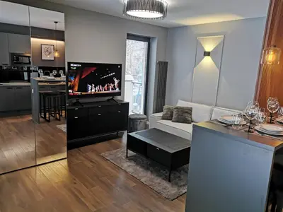 a living room with a couch and a tv and a kitchen at Apartament Raciborska 1 in Kraków