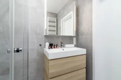 a bathroom with a white sink and a shower at Świtezianki Luxurious Apartments with Parking by Renters Prestige in Kraków