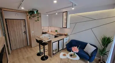 a living room with a blue couch and a kitchen at Magic House Apartament Proszowska 58 in Bochnia