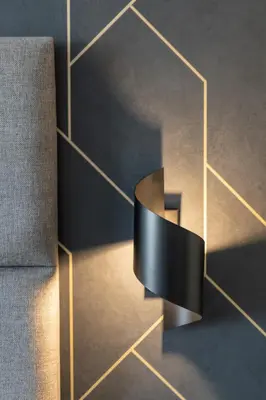 a black and gold object on a wall next to a chair at MILU Apartments Sebastiana in Kraków