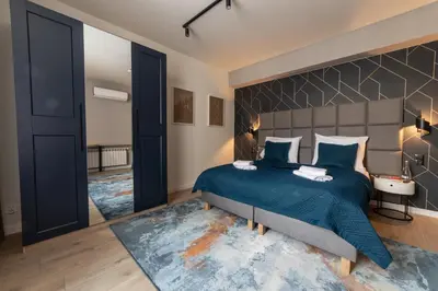 a bedroom with a large bed with a blue bedspread at MILU Apartments Sebastiana in Kraków