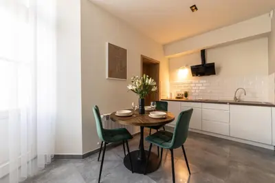 a kitchen with a wooden table and green chairs at MILU Apartments Sebastiana in Kraków