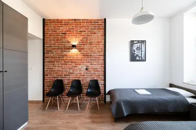 a bedroom with a brick wall and three black chairs at NEO UNIQUE & BRIGHT Apartments, FREE PARKING, 15min Old Town & Kazimierz - by Homelike Krakow in Kraków