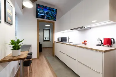 a kitchen with white cabinets and a wooden table at NEO UNIQUE & BRIGHT Apartments, FREE PARKING, 15min Old Town & Kazimierz - by Homelike Krakow in Kraków
