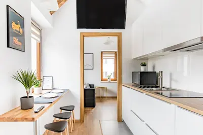a kitchen with white cabinets and a counter with stools at NEO UNIQUE & BRIGHT Apartments, FREE PARKING, 15min Old Town & Kazimierz - by Homelike Krakow in Kraków