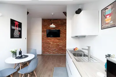 a kitchen with a white table and a brick wall at NEO SKY Apartment, FREE PARKING, 15 min walk Old Town&Kazimierz - by Homelike Krakow in Kraków