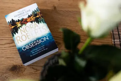 a book sitting on a table next to a flower at NEO SKY Apartment, FREE PARKING, 15 min walk Old Town&Kazimierz - by Homelike Krakow in Kraków