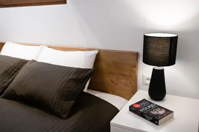 a bed with a lamp and a book on a night stand at NEO SKY Apartment, FREE PARKING, 15 min walk Old Town&Kazimierz - by Homelike Krakow in Kraków
