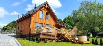 a large wooden house with a large deck at Sielski Zakątek Dąbrówka Domki in Dąbrówka