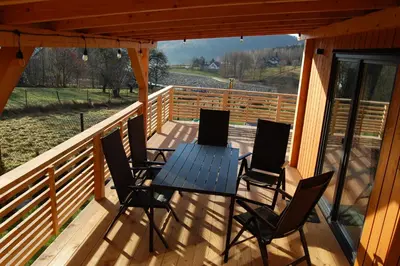 a wooden deck with a table and chairs on it at Sielski Zakątek Dąbrówka Domki in Dąbrówka