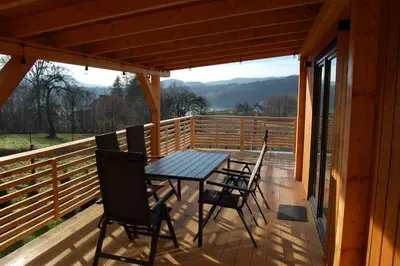 a table and chairs on the deck of a cabin at Sielski Zakątek Dąbrówka Domki in Dąbrówka