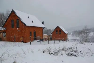 two large red barns with snow on them at Sielski Zakątek Dąbrówka Domki in Dąbrówka