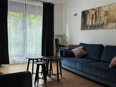 a living room with a blue couch and tables at AMBER APARTAMENt 127 in Kraków