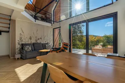 a living room with a wooden table and a large window at Drwalówka - Domek 