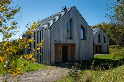a black house with a gambrel roof at Drwalówka - Domek 