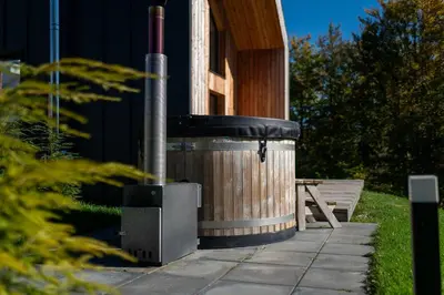 a hot tub outside of a house with a bench at Drwalówka - Domek 