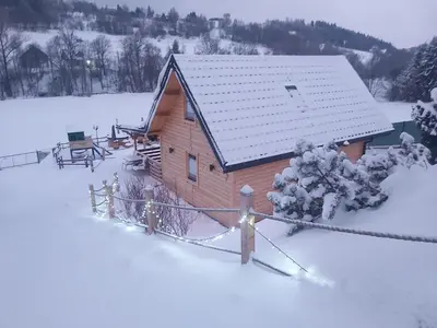 a wooden cabin with snow on the roof at Domek pod Hajdówką in Jordanów