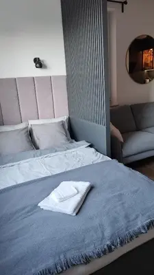 a bed with a towel on it with a couch at Apartment Between in Kraków