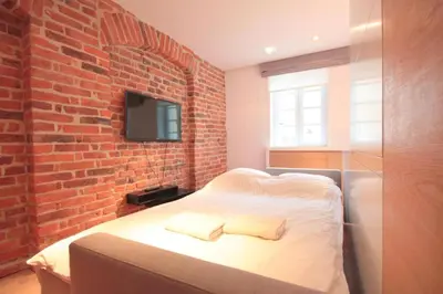 a bedroom with a bed with a brick wall at Modern & Resto Apartments in Kraków