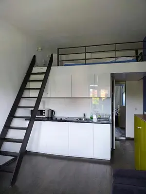 a kitchen with white cabinets and a loft bed at Room Tour Lubomirskiego 23 in Kraków