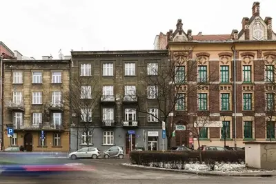 a large brick building with cars parked in front of it at Room Tour Lubomirskiego 23 in Kraków
