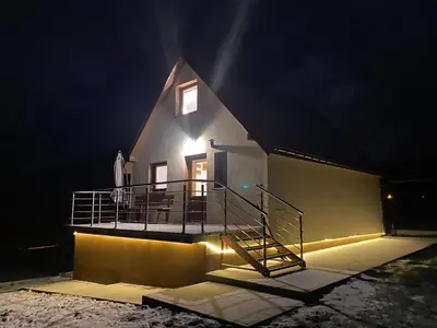 a house with a balcony and a staircase at night at Spacerowy Zakątek in Ślemień
