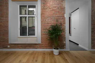 a brick wall with a window and a potted plant at RELAX APARTMENT (Netflix, PS4, fotel masujący) in Kraków