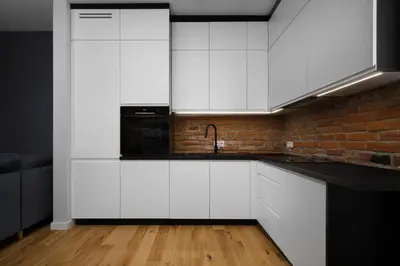 a kitchen with white cabinets and a brick wall at RELAX APARTMENT (Netflix, PS4, fotel masujący) in Kraków