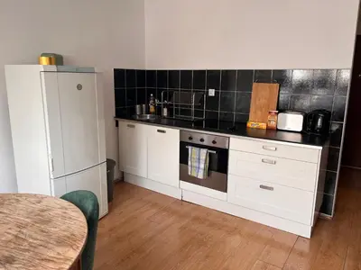 a kitchen with white cabinets and a black tiled wall at Appartement Vieille Ville in Kraków