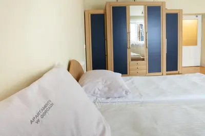 a bedroom with a white bed with a mirror at Apartamenty w Gorcach in Nowy Targ