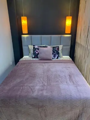 a bed with a purple comforter in a room at Petit Appartement in Kraków