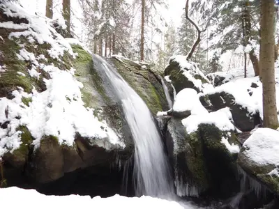 a waterfall is covered in snow in a forest at Sielsko Anielsko in Stryszawa