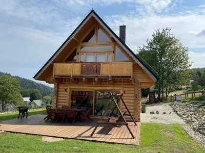 a log cabin with a deck with a table at Sielsko Anielsko in Stryszawa