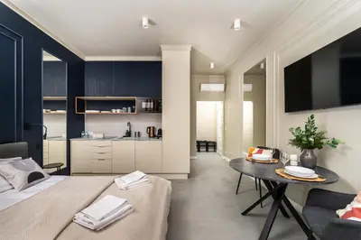 a bedroom with a bed and a table and a kitchen at Apartamenty Jubilat - KRK FOR STAY in Kraków