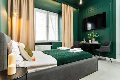 a green room with a bed and a table at Apartamenty Jubilat - KRK FOR STAY in Kraków