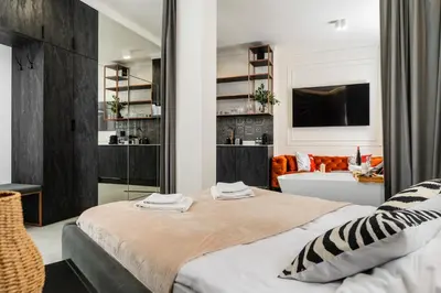 a bedroom with a bed and a living room at Apartamenty Jubilat - KRK FOR STAY in Kraków