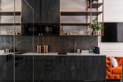 a kitchen with black cabinets and an orange couch at Apartamenty Jubilat - KRK FOR STAY in Kraków