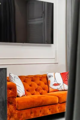 an orange couch with pillows on it under a mirror at Apartamenty Jubilat - KRK FOR STAY in Kraków