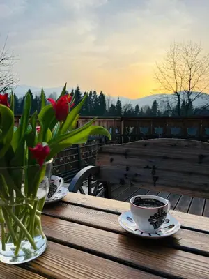 a table with two cups of coffee and a vase of flowers at Oskarówka domek w górach na odludziu z jacuzzi i sauną - kominek i Netflix in Szczawa
