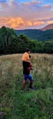 a man carrying a baby in a field at Oskarówka domek w górach na odludziu z jacuzzi i sauną - kominek i Netflix in Szczawa