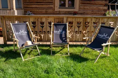 two chairs sitting in the grass in front of a fence at Oskarówka domek w górach na odludziu z jacuzzi i sauną - kominek i Netflix in Szczawa