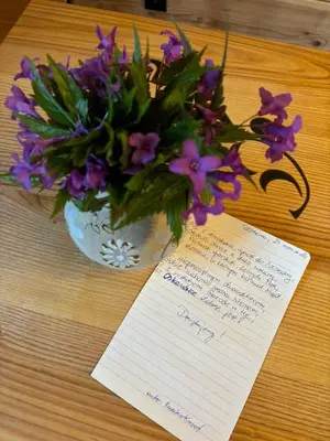 a vase of purple flowers and a note on a table at Oskarówka domek w górach na odludziu z jacuzzi i sauną - kominek i Netflix in Szczawa