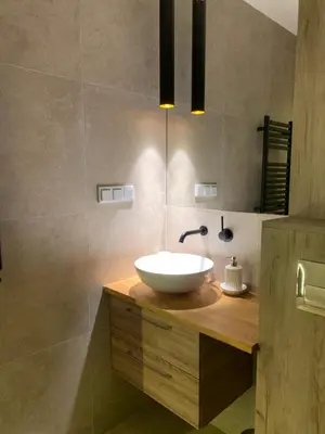 a bathroom with a white bowl sink on a wooden counter at Moderno Apartament in Kraków